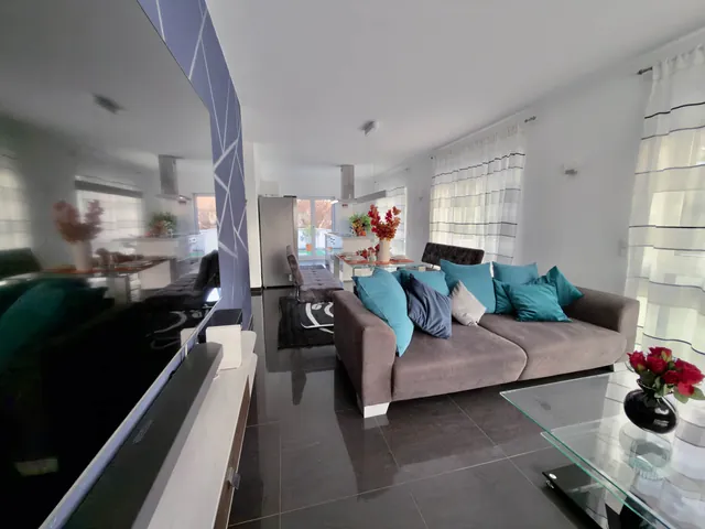 Wohnraum der Ferienwohnung Thermenblick mit Sofa und Fensterfront